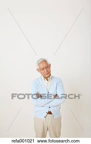 Stock Image - Senior adult Japanese man against white wall. Fotosearch