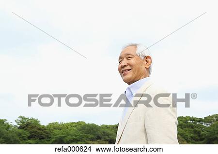 Picture - Senior adult Japanese man in a park. Fotosearch