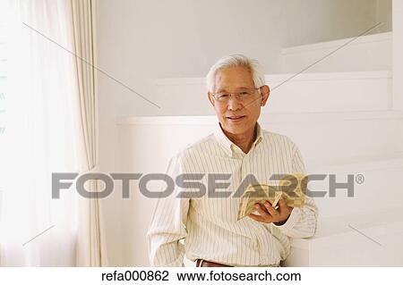 Stock Image - Senior adult Japanese man with book. Fotosearch