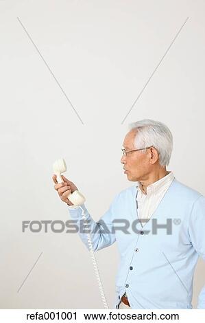 Senior adult Japanese man with phone against white wall View Large Photo Image Stock Image - Senior adult Japanese man with phone against white wall. Fotosearch