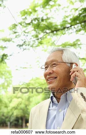 Senior adult Japanese man with smartphone in a park View Large Photo Image Stock Photo - Senior adult Japanese man with smartphone in a park. Fotosearch