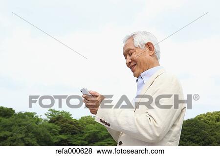 Senior adult Japanese man with smartphone in a park View Large Photo Image Stock Photo - Senior adult Japanese man with smartphone in a park. Fotosearch
