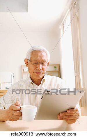 Stock Image - Senior adult Japanese man with tablet. Fotosearch