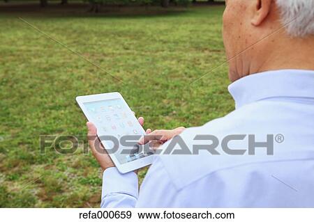 Senior adult Japanese man with tablet in a park View Large Photo Image Stock Photo - Senior adult Japanese man with tablet in a park. Fotosearch