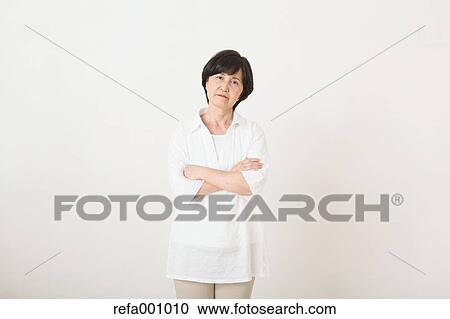 Stock Image - Senior adult Japanese woman against white wall. Fotosearch