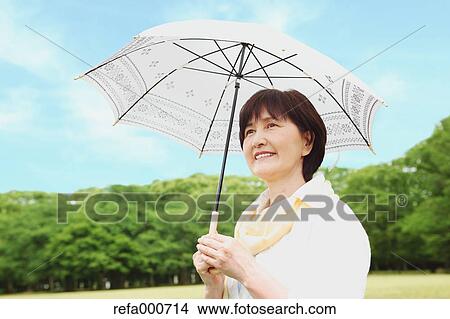 Picture - Senior adult Japanese woman with parasol in a park. Fotosearch