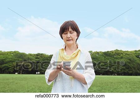 Senior adult Japanese woman with smartphone in a park View Large Photo Image Stock Image - Senior adult Japanese woman with smartphone in a park. Fotosearch