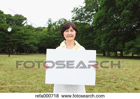 Stock Photo - Senior adult Japanese woman with whiteboard in a park. Fotosearch