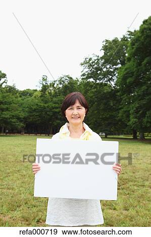 Stock Photo - Senior adult Japanese woman with whiteboard in a park. Fotosearch