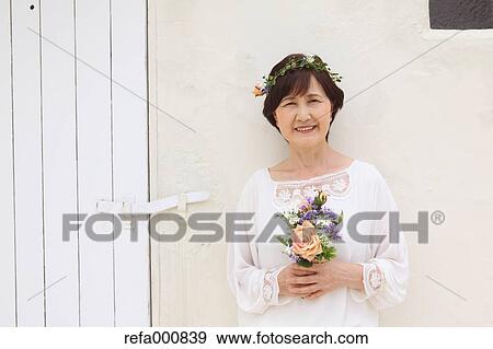 Stock Photo - Senior adult Japanese woman with bouquet smiling. Fotosearch