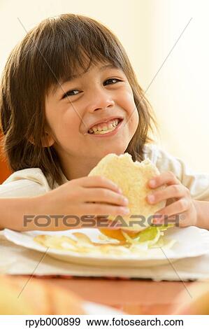 Young boy eating in the kitchen View Large Photo Image Stock Photo - Young boy eating in the kitchen. Fotosearch