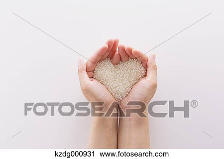 Stock Image - Young Japanese woman holding rice in her hands. Fotosearch