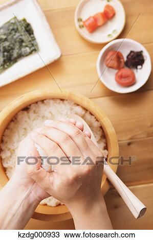 Stock Image - Young Japanese woman preparing Onigiri rice balls. Fotosearch