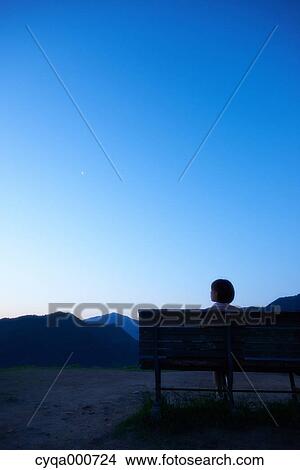 Young Japanese woman sitting on a bench in the countryside View Large Photo Image Picture - Young Japanese woman sitting on a bench in the countryside. Fotosearch