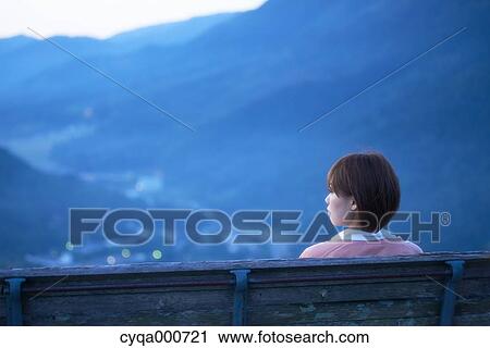 Young Japanese woman sitting on a bench in the countryside View Large Photo Image Stock Image - Young Japanese woman sitting on a bench in the countryside. Fotosearch