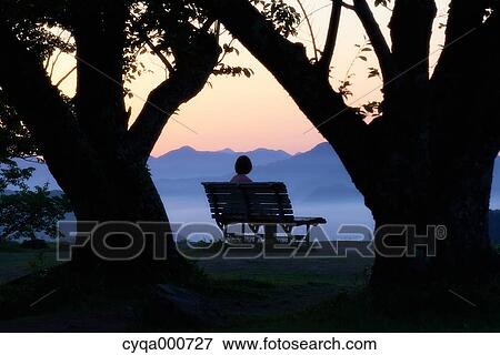 Young Japanese woman sitting on a bench in the countryside View Large Photo Image Stock Photo - Young Japanese woman sitting on a bench in the countryside. Fotosearch