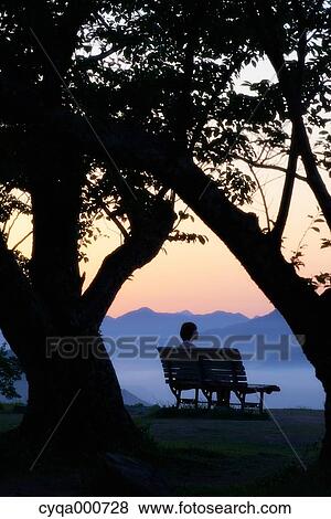 Young Japanese woman sitting on a bench in the countryside View Large Photo Image Stock Photo - Young Japanese woman sitting on a bench in the countryside. Fotosearch