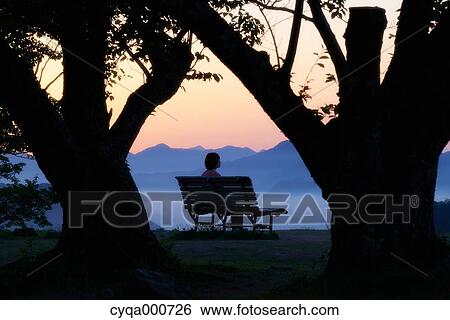 Young Japanese woman sitting on a bench in the countryside View Large Photo Image Stock Photograph - Young Japanese woman sitting on a bench in the countryside. Fotosearch
