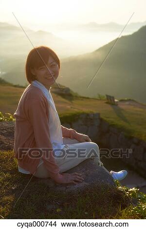 Young Japanese woman sitting on grass in the countryside View Large Photo Image Picture - Young Japanese woman sitting on grass in the countryside. Fotosearch