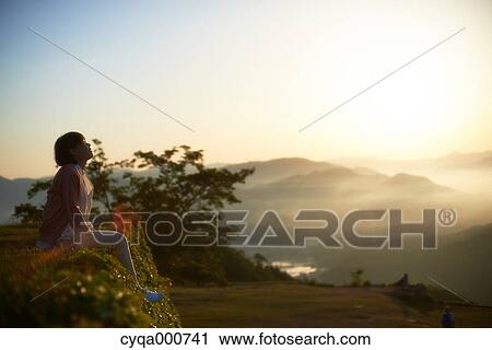 Young Japanese woman sitting on grass in the countryside View Large Photo Image Stock Image - Young Japanese woman sitting on grass in the countryside. Fotosearch