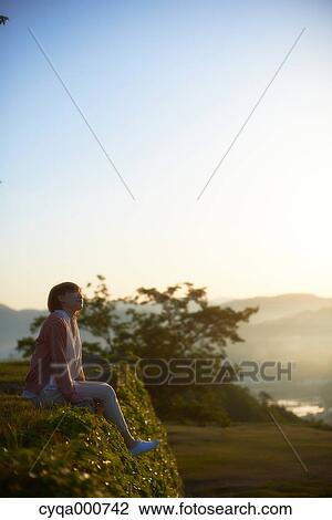 Young Japanese woman sitting on grass in the countryside View Large Photo Image Stock Image - Young Japanese woman sitting on grass in the countryside. Fotosearch