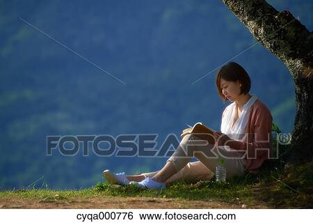 Young Japanese woman sitting with book in the countryside View Large Photo Image Stock Photograph - Young Japanese woman sitting with book in the countryside. Fotosearch