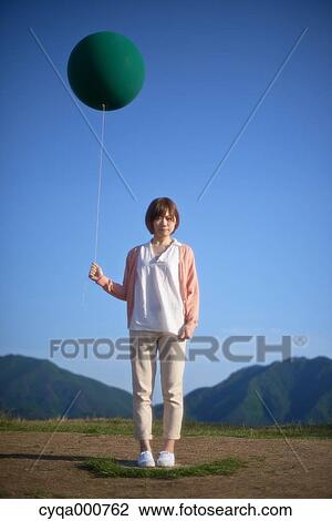 Young Japanese woman with green balloon in the countryside View Large Photo Image Stock Image - Young Japanese woman with green balloon in the countryside. Fotosearch