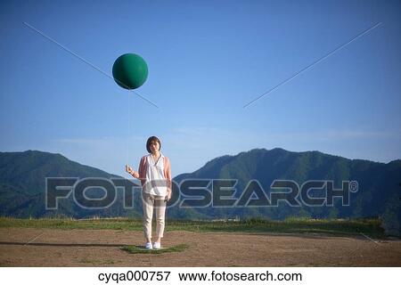 Young Japanese woman with green balloon in the countryside View Large Photo Image Stock Photo - Young Japanese woman with green balloon in the countryside. Fotosearch