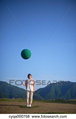 Young Japanese woman with green balloon in the countryside View Large Photo Image Stock Photo - Young Japanese woman with green balloon in the countryside. Fotosearch