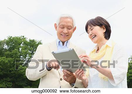 Stock Image - Senior adult Japanese couple in a park. Fotosearch