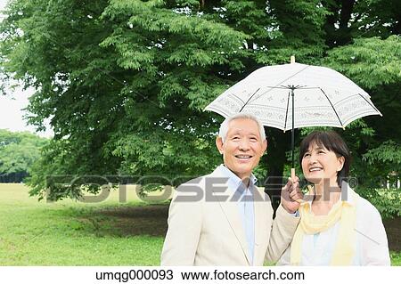 Stock Image - Senior adult Japanese couple in a park. Fotosearch