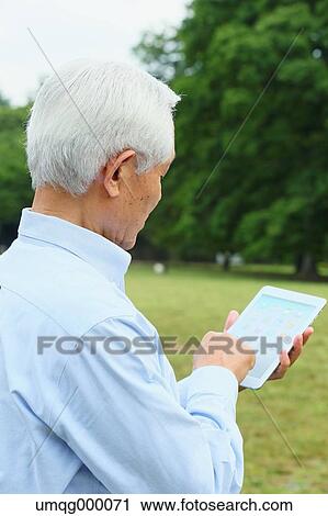Senior adult Japanese man with tablet in a park View Large Photo Image Stock Image - Senior adult Japanese man with tablet in a park. Fotosearch