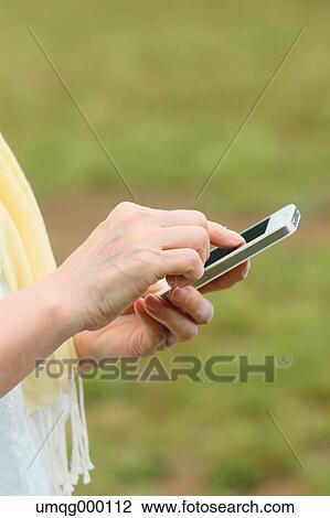 Stock Image - Senior adult Japanese woman with smartphone in a park. Fotosearch