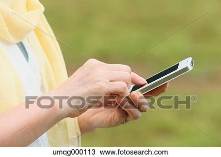 Stock Image - Senior adult Japanese woman with smartphone in a park. Fotosearch