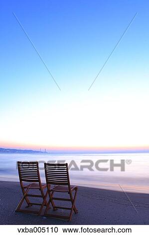 Stock Image - Chairs At The Beach At Sunset. Fotosearch
