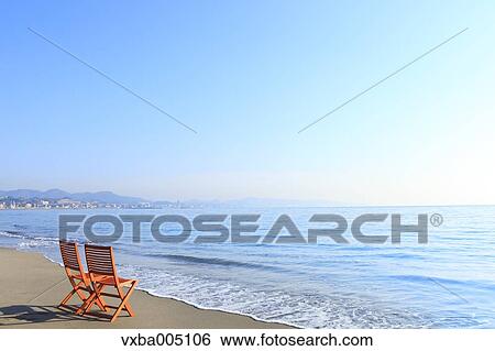 Stock Photograph - Chairs At The Beach At Sunset. Fotosearch