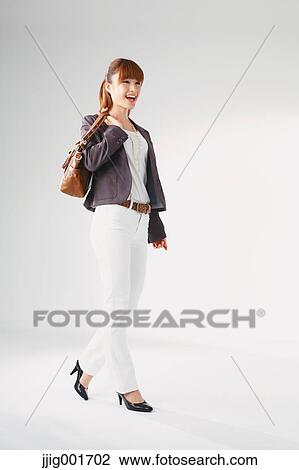 Stock Image - Full length portrait of Japanese young businesswoman against white background. Fotosearch