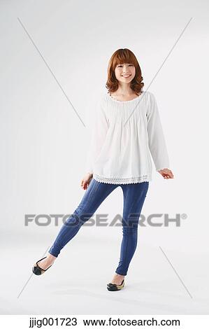 Stock Image - Full length portrait of young Japanese woman against white background. Fotosearch