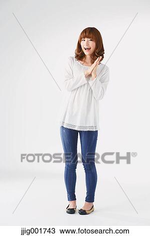 Stock Image - Full length portrait of young Japanese woman against white background. Fotosearch