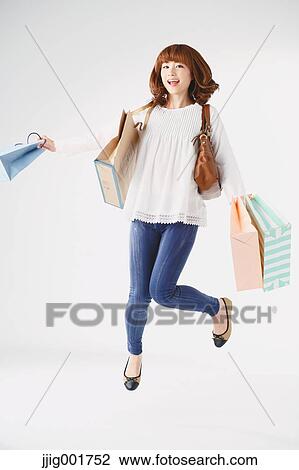 Stock Image - Full length portrait of young Japanese woman against white background. Fotosearch