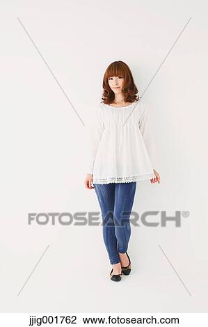 Stock Image - Full length portrait of young Japanese woman against white background. Fotosearch