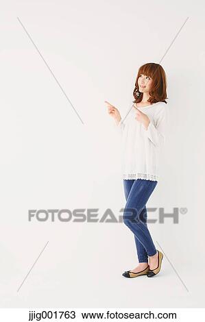 Stock Image - Full length portrait of young Japanese woman against white background. Fotosearch