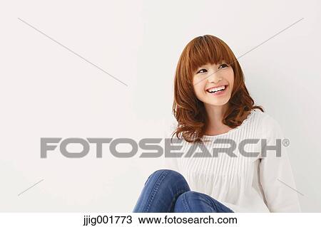 Stock Image - Half length portrait of young Japanese woman against white background. Fotosearch