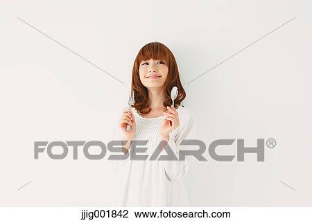 Stock Image - Half length portrait of young Japanese woman against white background. Fotosearch