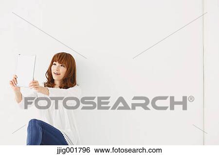 Stock Photograph - Half length portrait of young Japanese woman against white background. Fotosearch
