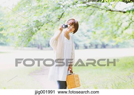 Stock Image - Portrait of young Japanese woman in a park. Fotosearch