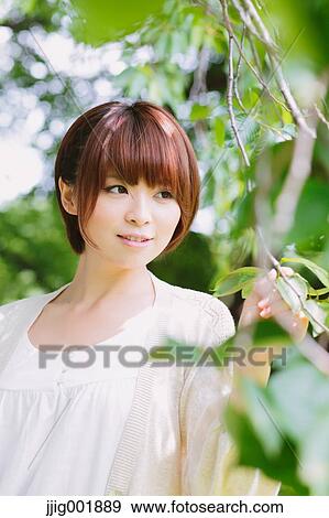 Stock Photo - Portrait of young Japanese woman in a park. Fotosearch