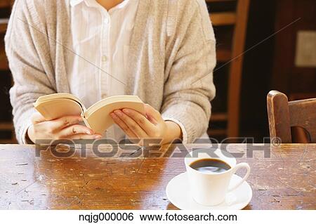 Stock Photograph - Young Japanese Woman Reading A Book In A Cafe. Fotosearch