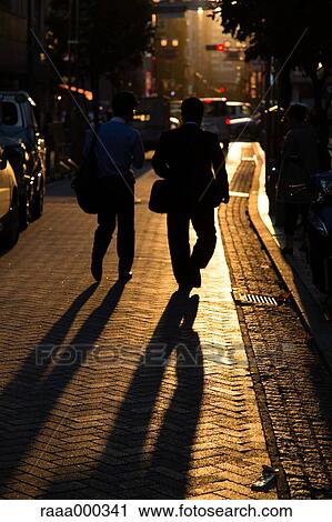 Stock Image - Businessmen walking at sunset. Fotosearch