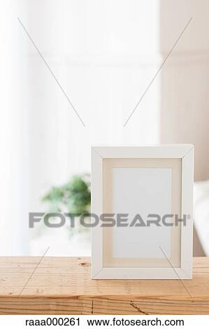 Stock Image - Empty photo frame on wooden table. Fotosearch
